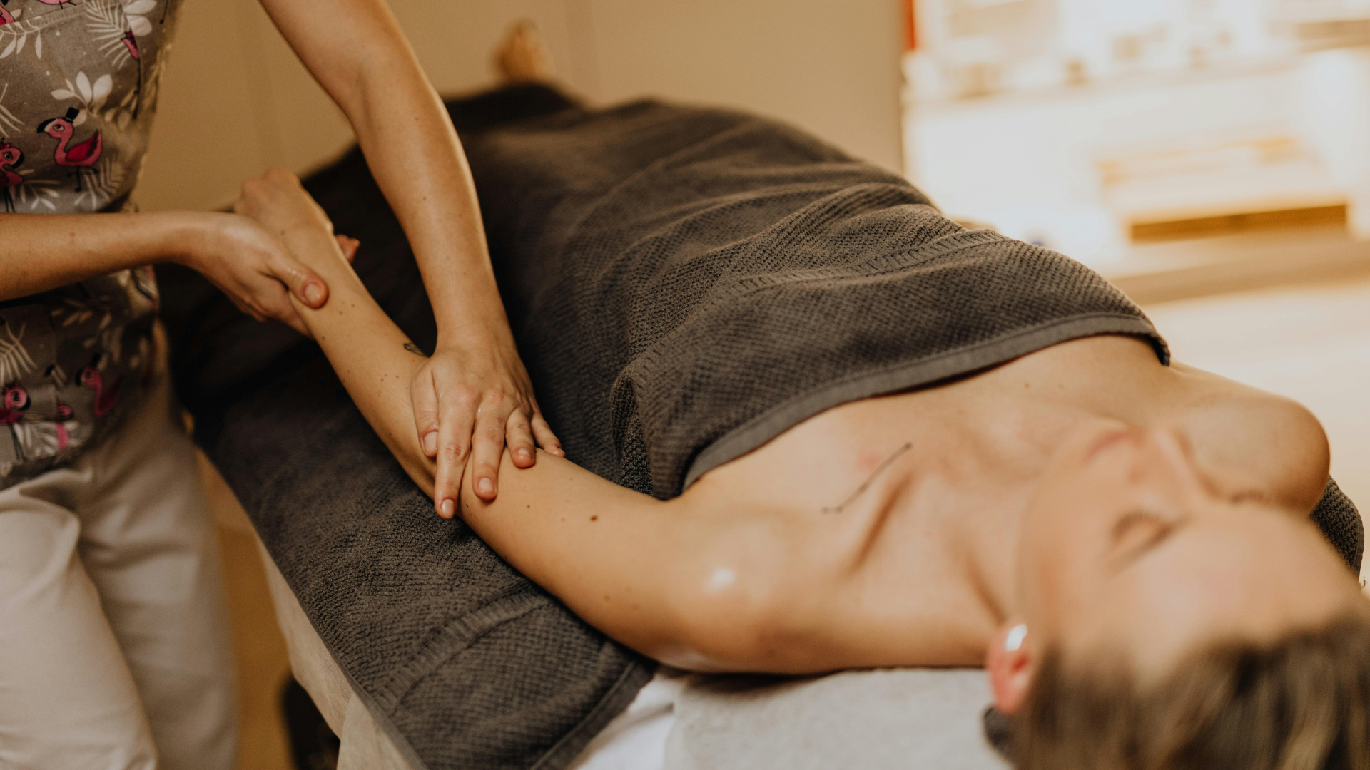 Tratamento para tendinites e bursites na Jéssica Pereira Fisioterapia. Uma especialista realiza uma massagem terapêutica e manobras de libertação tecidular no braço e punho de uma paciente para reduzir a inflamação e a dor.